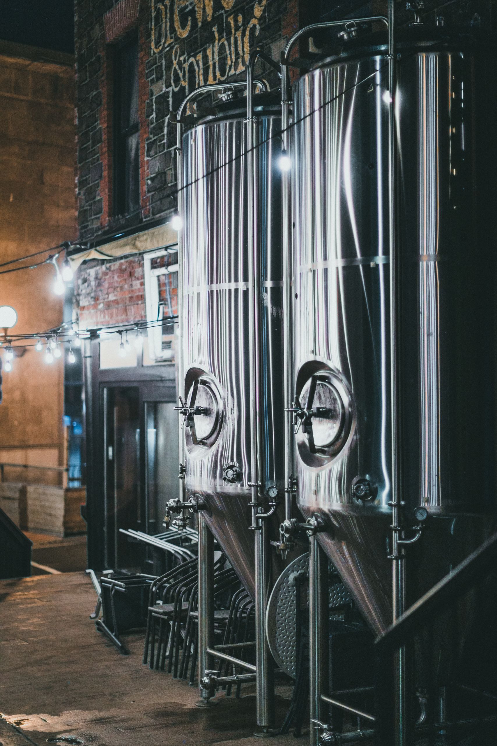 Metal brewing vats at night in an outdoor industrial setting.